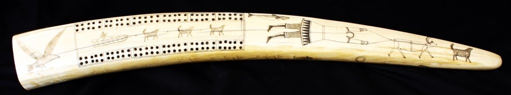 Vintage Native Alaskan Scrimshaw Walrus Tusk: Est. $900-$1500 Vintage Native Alaskan Scrimshawed Walrus Tusk Cribbage Board 23 3/4" long. The walrus tusk dating to circa 1910 extensively decorated to top, bottom and sides with images from daily N