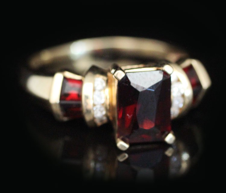 Ladies Garnet & Diamond Ring in yellow gold: Est. $500-$750 Ladies Garnet and diamond ring in yellow gold. 14kyg 4.99 grams. Center stone Garnet 6.04 X 8.11 X 3.47mm rectangular mixed cut. Sides (4) Garnets 2.50 X 2.10mm each tapered step cut. D