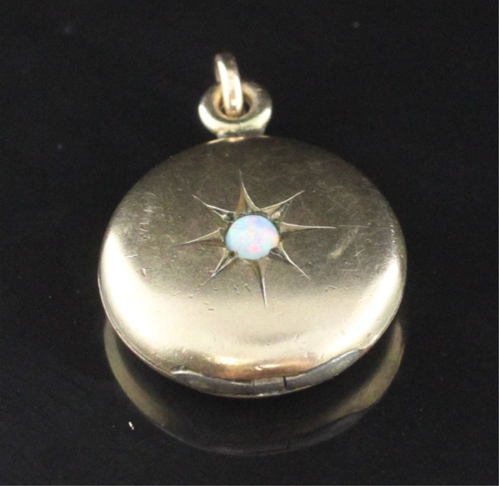 Jewelry-Petite Round Locket Pendant: ESt. $20-$50 Petite round locket pendant in yellow gold tone. Gold filled. Center stone opal round cabachon 2.50mm. Marked D&C. 1/2 inch diameter.