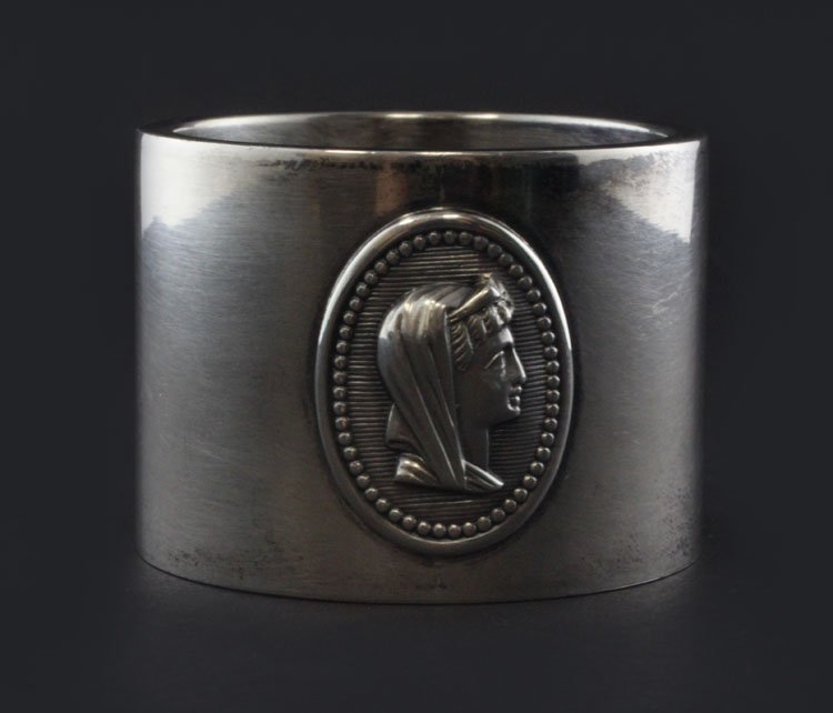 Silver Medallion Napkin Ring: Est. $ 70 - 110 Silver Medallion Napkin Ring Possibly sterling no marks, has a repousse oval of a women's head, no marks observed one side engraved Nelly, circa early 20th century. 1 7/8" diameter x 1