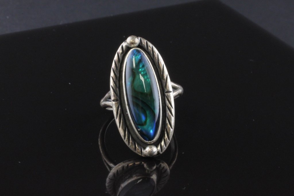 Native American Abalone Ring in Sterling: Est. $ 50-90. Native American Abalone Ring in Sterling weighs 4.24 grams. Oval polished abalone. Wonderful blue green colors. 19.8x6.91mm. Southwest Style geometric pattern 1" at widest point.