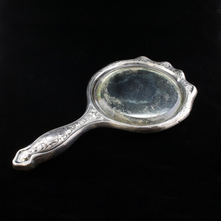 Sterling Hand Mirror: Est. $ 70 - 90 Sterling Hand Mirror . The mirror is covered in a floral and geometric repousse design. On the front of the handle is marked sterling but no other observed marks. On the reverse of the