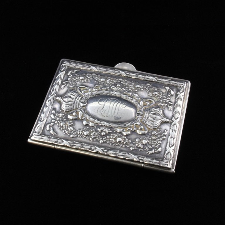 Vintage Sterling Case: Est $ 30-60 Sterling case that is possibly a card case, Aide de memoir or a necessaire case. The case is decorated in a repousse crowns, ribbons, flowers and bordered by a geometric almost lattice pat