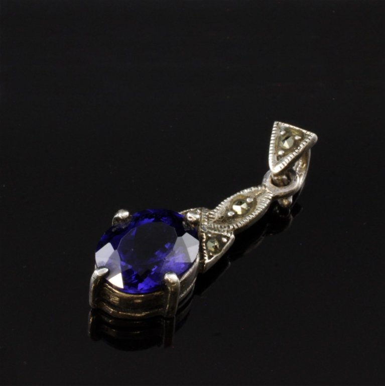 Gemstone Drop Pendant in Sterling: Est. $ 25 - 50. Gemstone Drop Pendant in Sterling . 2.0gr tw. Gemstone: Purple with blue tone oval, faceted 6.96 X 9.15mm. Accented with Marcasite 1" overall length.