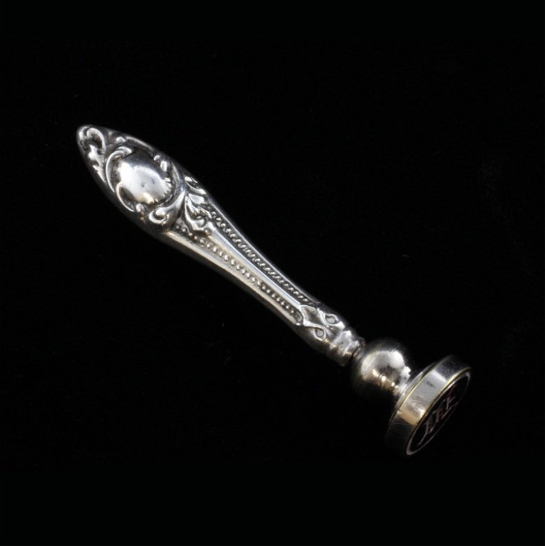 Silver Wax Seal Stamp: Est $ 45-90 Wax seal stamp of the letter M, silver handle with a silver plated base. The handle is ornamented with a beaded and relief swirl design, the stamp measures 2 1/4" tall x 1/2" wide and weig