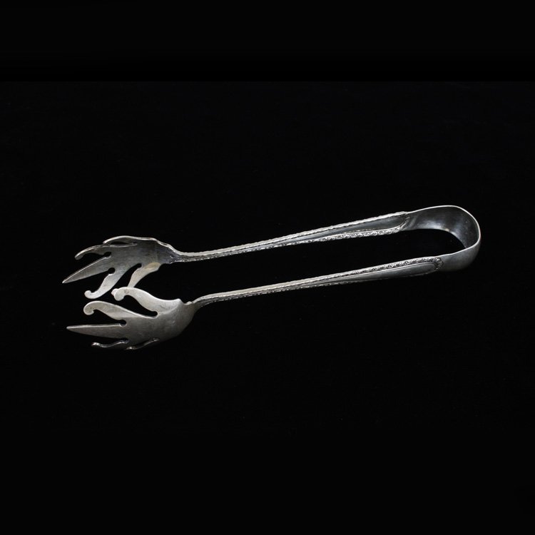 J.E. Caldwell & Co. Sterling Tongs: Est $ 80-120 Sterling tongs marked J.E. Caldwell & Co. and what appears to be the Davis & Galt Fleur-de-lis inside a shield next to the word sterling. The handles ornamented in a floral border termina