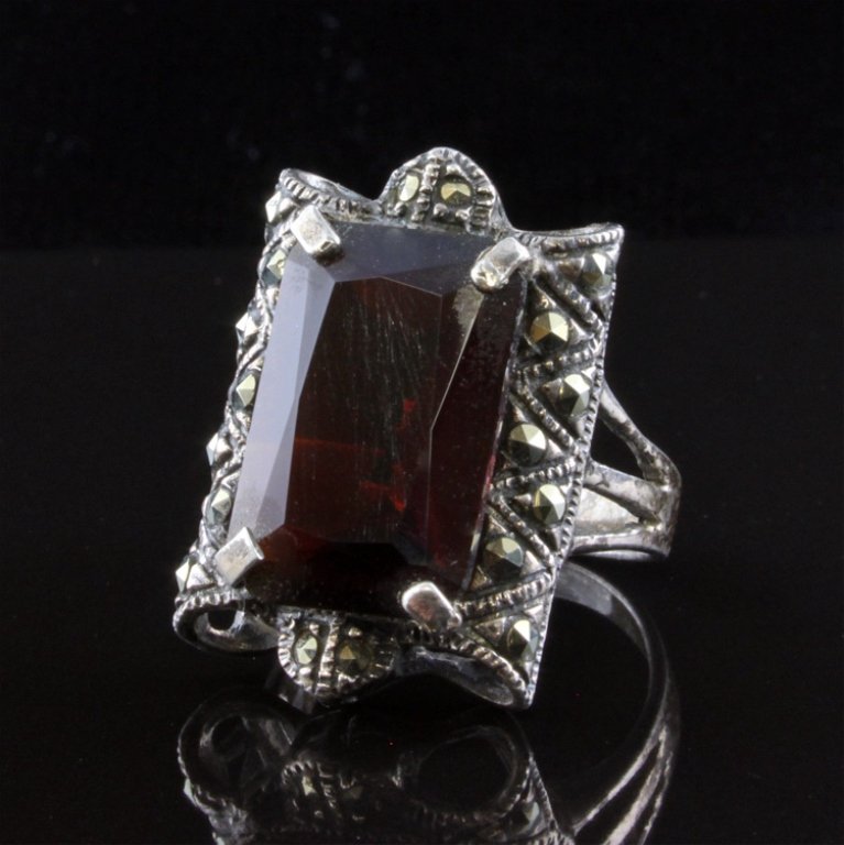 Vintage Garnet and Marcasite Ring in Sterling: Est. $ 75 - 125 Vintage Garnet and Marcasite Ring in Sterling 6.59 gr tw. Gemstone: Center - Garnet. 16.9x 10.9mm rectangular mixed cut. Marcasite accents. Mark .925