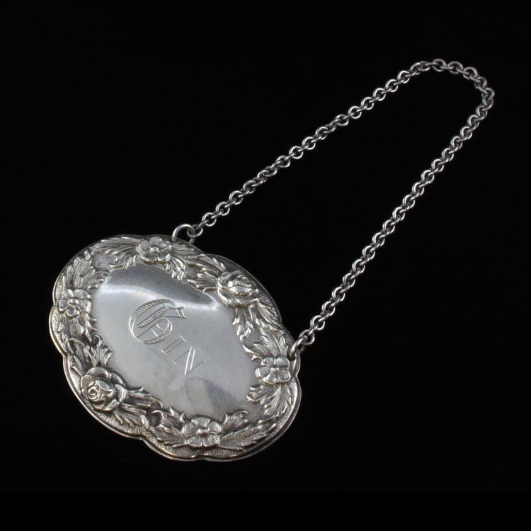 Sterling Gin S. Kirk & Sons Decanter Tag: Est $ 60-120 Sterling decanter lable tag etched with the word Gin in the center of a floral low relief boarder. The reverse of the tag is marked sterling, S. Kirk & Sons along with the letter 4. The t