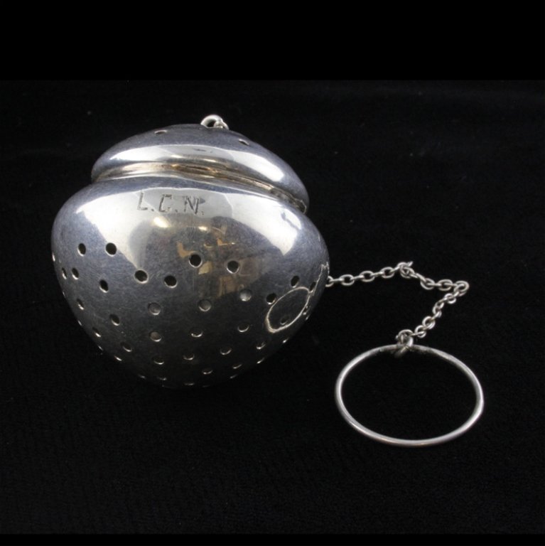 James E. Blake Co. Tea Infuser Ball: Est $ 70-130 Sterling tea infuser ball marked by the James E. Blake Co. The ball is reticulated with a hinged lid with a chain terminating into a loop. The lid is marked sterling and bears the makers 