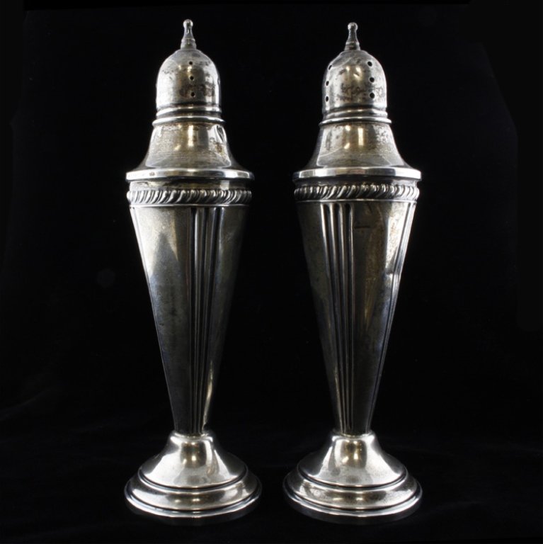 Hamilton Sterling Salt & Pepper Shaker: Est $ 100-200 Weighted sterling salt and pepper shaker made by Hamilton with a braided border and a pierced lid that is topped by a finial. The shakers measure 6 1/4" tall x 2" at the widest point.