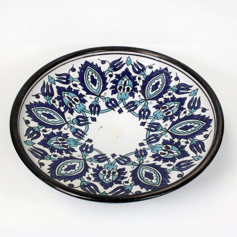 Decorative Signed Middle Eastern Wall Art: Est $ 150-300 Signed Middle Eastern wall art with a blue and green floral motif. The bowl has a black line around the lip with a small chip. It measures 15" in diameter x 4 1/4" tall.