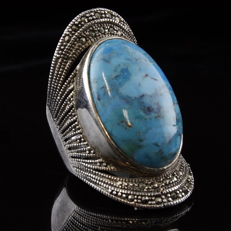 Sterling, Turquoise and Marcasite Fashion Ring: Est. $ 40 - 60 Sterling, Turquoise and Marcasite Fashion Ring 16.3 gr tw. Large turquoise cabochon measuring 1" x 5/8". The ring is 1.5" at its widest point.