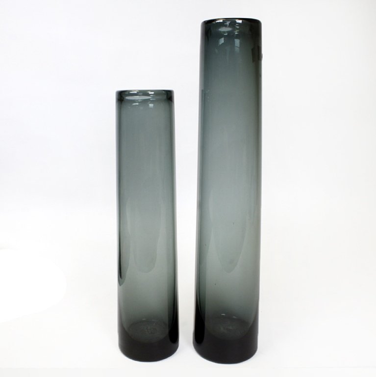 Set of Two Holmegaard Cylindrical Vases: Est $ 150-300 Set of two cylindrical smoked glass vases both marked Holmegaard underneath. The larger vase measures 14 1/2" tall and the other is 12" tall. Third Party Shipping.
