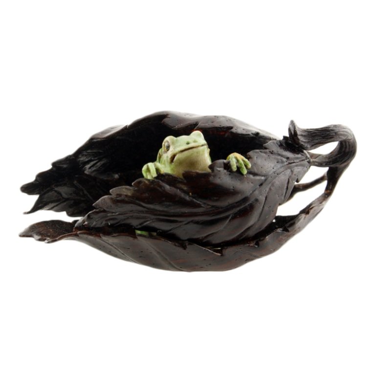 Toukoku Carved Frog in Leaves Netsuke: Est. $400 - 700 Toukoku Carved Frog in Leaves Netsuke. Finely carved piece with polychromed bone frog in wood carved leaves. Marked with toukoku Kakihan. Measures 2 1/4 x 1 1/4".