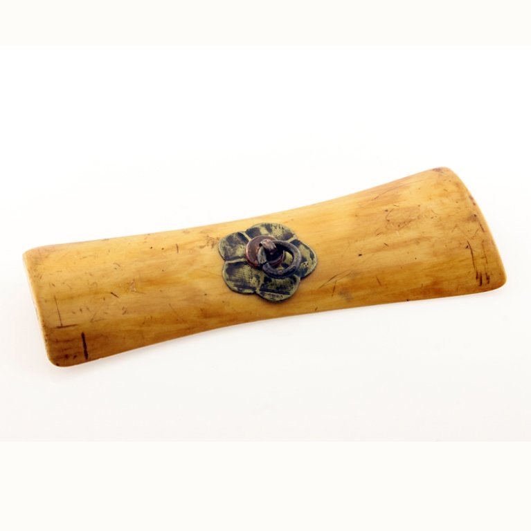 Flat Bone Toggle or Netsuke: Est. $125 - 200 Flat Bone Toggle or Netsuke. Bone toggle or netsuke with decorative bale and paddle design on reverse. Measures 4 1/8" long and 1 1/2 inches at widest point.