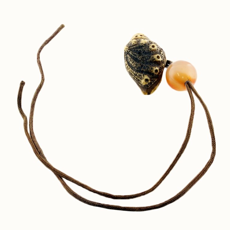 Snail Netsuke with Ojime Bead: Est. $75 - 125 Snail Netsuke with Ojime Bead. Bone netsuke carved into snail. Chord and ojime bead. Netsuke measures 1 3/4 x 1 1/8 x 1/2".