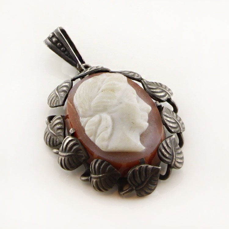 Vintage Carnelian Cameo Sterling Pendant: Est. $50 - 100 Vintage Carnelian Cameo Sterling Pendant. 4.2 gr tw. Sterling floral oendant with Carnelian carved cameo. 1 1/4 x 3/4".