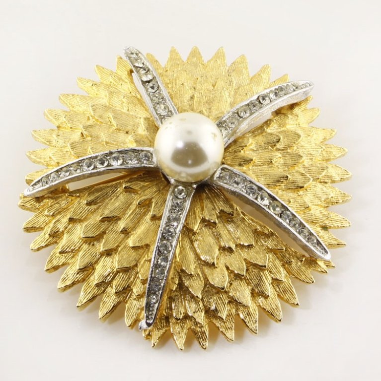 Vintage Hattie Carnegie Pin Brooch: Est. $100 - 200 Vintage Hattie Carnegie Pin Brooch. Hattie Carnegie pin brooch. Two tone silver and gold with pearl and rhinestone accents. 2" diameter. Marks: Hattie Carnegie.