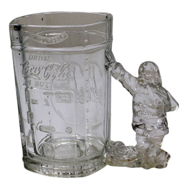 Coca Cola Serve Yourself Mug: Est. $ 10 - 15 Coca Cola Serve Yourself Mug. Glass mug with Santa Claus handle is 5.75 inches tall with old fashion coke machine impressed upon one side and bottle on the other.