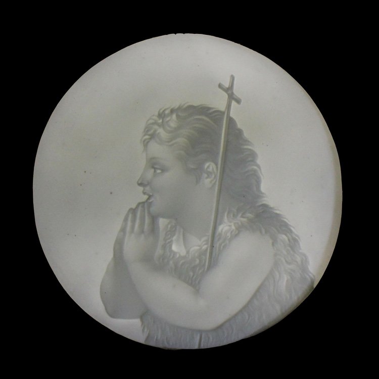 Young John the Baptist Lithophane: Est. $ 160 - 240 Young John the Baptist Lithophane . A 16.25inch tall walnut candle shield containing a 6inch round lithophane depicting a young John the Baptist in a hair shirt with a staff surmounte