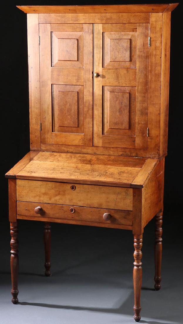 A GOOD EARLY AMERICAN SLANT TOP PLANTATION DESK: A GOOD EARLY AMERICAN SLANT TOP PLANTATION DESK, CIRCA 1810. In cherry wood with blind two paneled door top raised on a turned leg base with slanted desk opening to interior compartments and two drawe