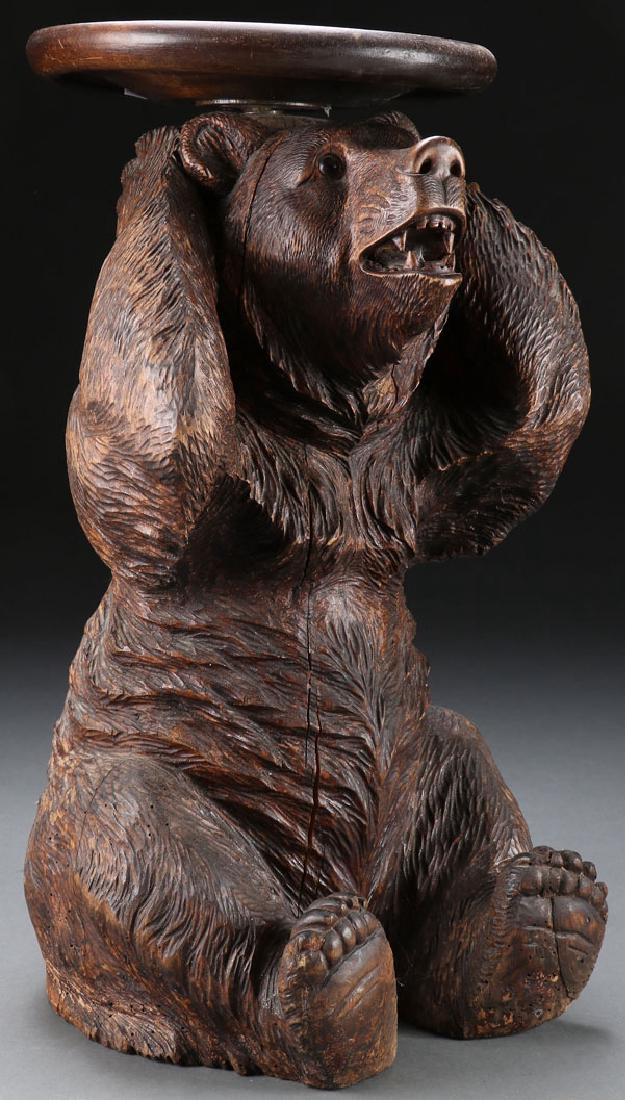 BLACK FOREST CARVED BEAR PIANO STOOL: A SWISS BLACK FOREST CARVED FIGURAL BEAR PIANO STOOL, CIRCA 1900. Finely carved in full round. The seated bear with open mouth and glass eyes, and with arms behind head and from which sprouts a thread
