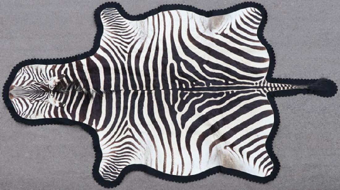 A LARGE ZEBRA SKIN RUG: A LARGE ZEBRA SKIN RUG. Backed in felt with scalloped borders. Greatest length 117 inches. SHIPPING NOTICE: Jackson’s is your sole and only source for one stop packing and shipping. With over 50 yea