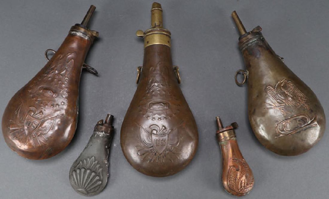 CIVIL WAR ERA POWDER FLASKS: CIVIL WAR ERA POWDER FLASKS. Comprising three large copper examples displaying Federal Eagle and with suspension loops. Together with a smaller copper model with eagle and a pewter clam shell example