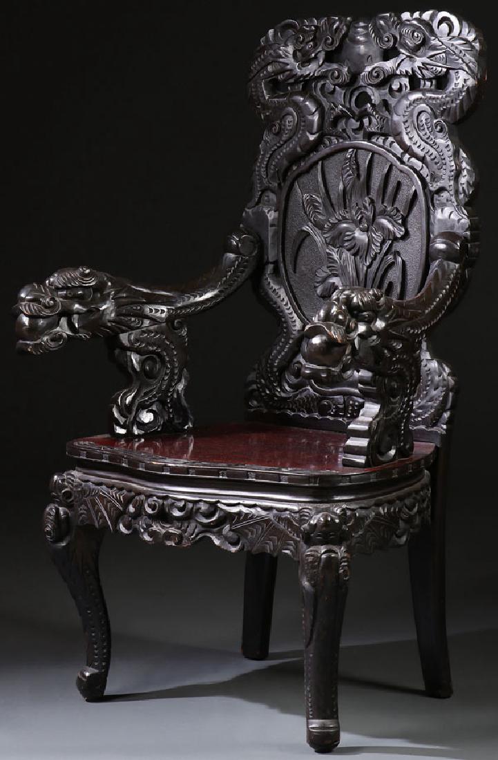 A JAPANESE CARVED EBONIZED WOOD DRAGON ARMCHAIR: A JAPANESE CARVED EBONIZED WOOD DRAGON ARMCHAIR, FIRST HALF OF THE 20TH CENTURY. Approximate height 45 inches (114.3 cm). The backrest ornately carved in open work with dragons, cattails, and floral f