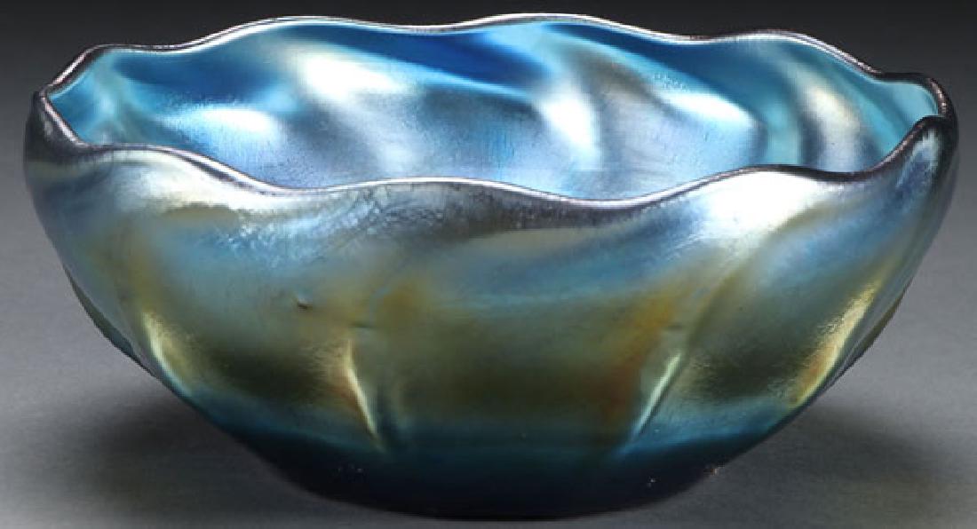 AN L. C. TIFFANY BLUE FAVRILLE ART GLASS BOWL: AN L. C. TIFFANY BLUE FAVRILLE ART GLASS BOWL, EARLY 20TH CENTURY. With twisted rib and scalloped rim. With a silvery blue iridized finish and gold highlights. The base inscribed 1284-L.C.T. Diameter 