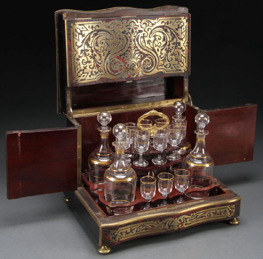 A 19TH CENTURY FRENCH BOULLE TANTALUS: A 19TH CENTURY FRENCH BOULLE TANTALUS. The multi-hinged case overlaid with tortoise shell and gilt bronze scrolled inlays opening to reveal a multi-tiered mahogany caddy fitted with four blown glass d
