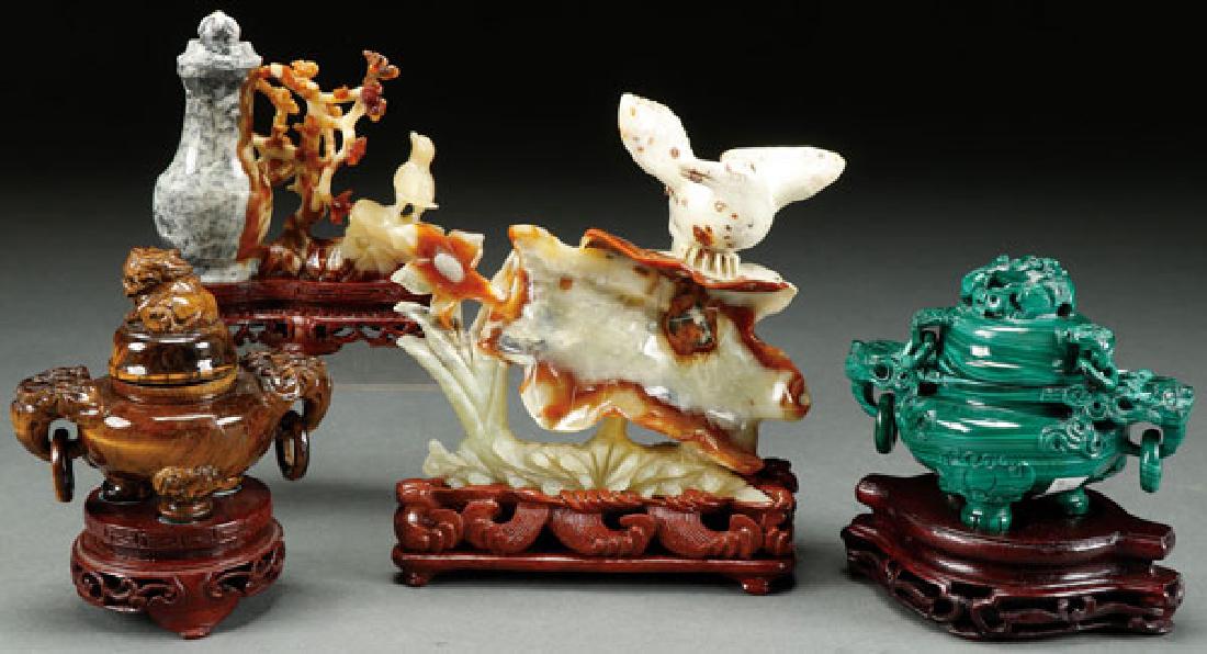 FOUR CHINESE CARVED HARDSTONE FIGURES AND CENSERS: FOUR CHINESE CARVED HARDSTONE FIGURES AND CENSERS. Comprising a bird on leaf pad, a bird with floral tree and urn, a tiger-eye tripod censer, and a malachite tripod censer. The largest 6 inches (5.3 c