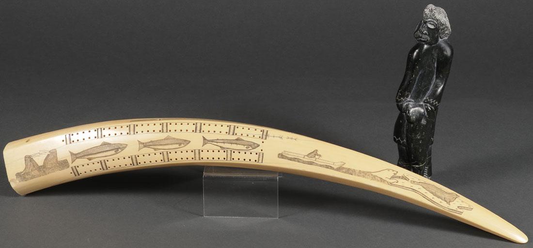 A SCRIMSHAW WALRUS TUSK CRIBBAGE BOARD: A LARGE AND IMPRESSIVE SCRIMSHAW WALRUS TUSK CRIBBAGE BOARD. The top with cribbage peg holes and scrimshawed with scenes of walrus, salmon, polar bear hunting, and the verso engraved with a map of the