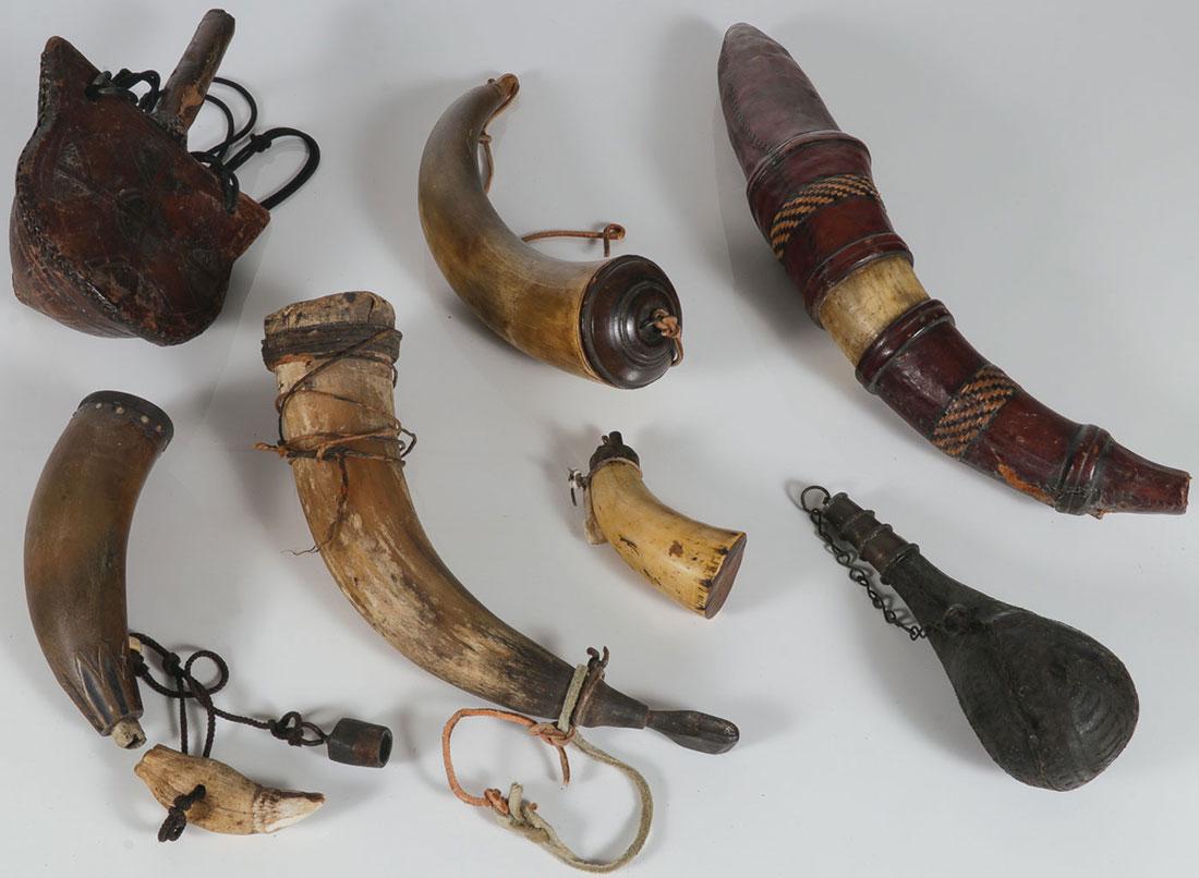 SEVEN POWDER HORNS/FLASKS, 19TH AND 20TH CENTURY: SEVEN POWDER HORNS/FLASKS, 19TH AND 20TH CENTURY. Comprising various materials (horn, leather) representing a variety of cultures and time periods. Greatest length 17 inches (43 cm). SHIPPING NOTICE:
