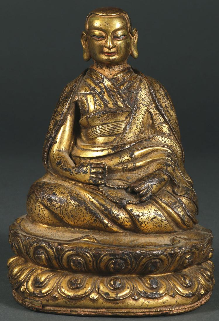 A SINO-TIBETAN GILT COPPER FIGURE OF A MONK: A SINO-TIBETAN GILT COPPER SEATED FIGURE OF A PRAYING MONK, 18TH CENTURY. Seated on a double lotus throne and holding a prayer rope, the face with traces of polychrome, sealed base engraved with singl