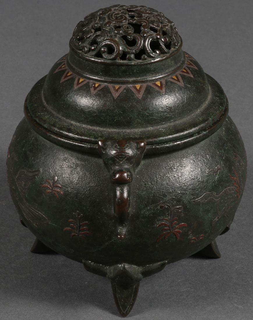 A BRONZE AND MIXED METAL FOOTED INCENSE BURNER: AN INTERESTING CHINESE BRONZE AND MIXED METAL FOOTED INCENSE BURNER. The sides decorated with phoenix and deer with elephant head handles and pierced fitted lid. Faint mark on underside of base. Heigh