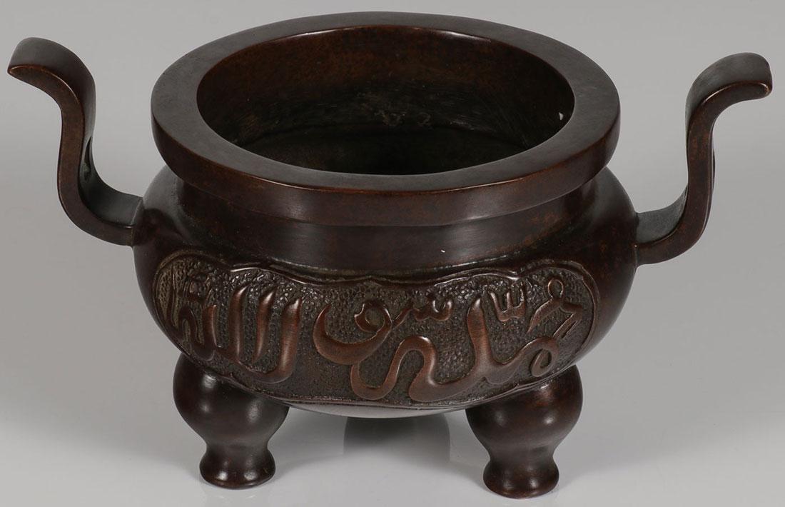 A CHINESE BRONZE INCENSE BURNER: A CHINESE BRONZE INCENSE BURNER. Of traditional form resting on three raised feet, the sides sculpted with Arabic inscriptions and underside of base with archaic reign mark. Height 4.75 incense (12 cm