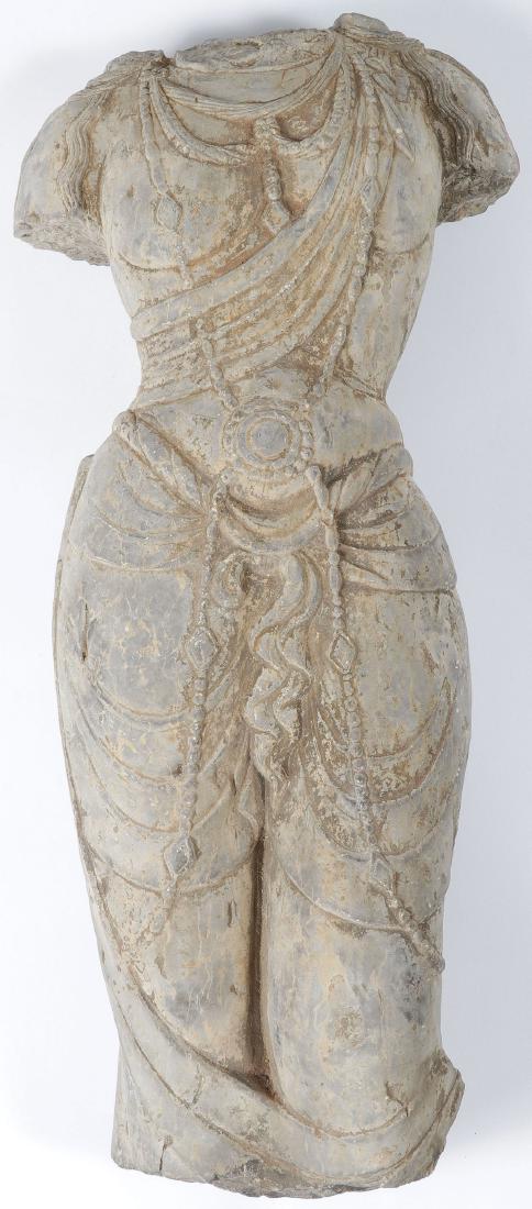 A CARVED/CAST STONE TORSO IN ANCIENT STYLE: A CARVED OR CAST STONE? TORSO, IN ANCIENT STYLE. Finely carved in full round with cascading hair on the shoulders and deep folds in the fabric and adorned with jewelry. Height 24.5 inches (62 cm). SHI