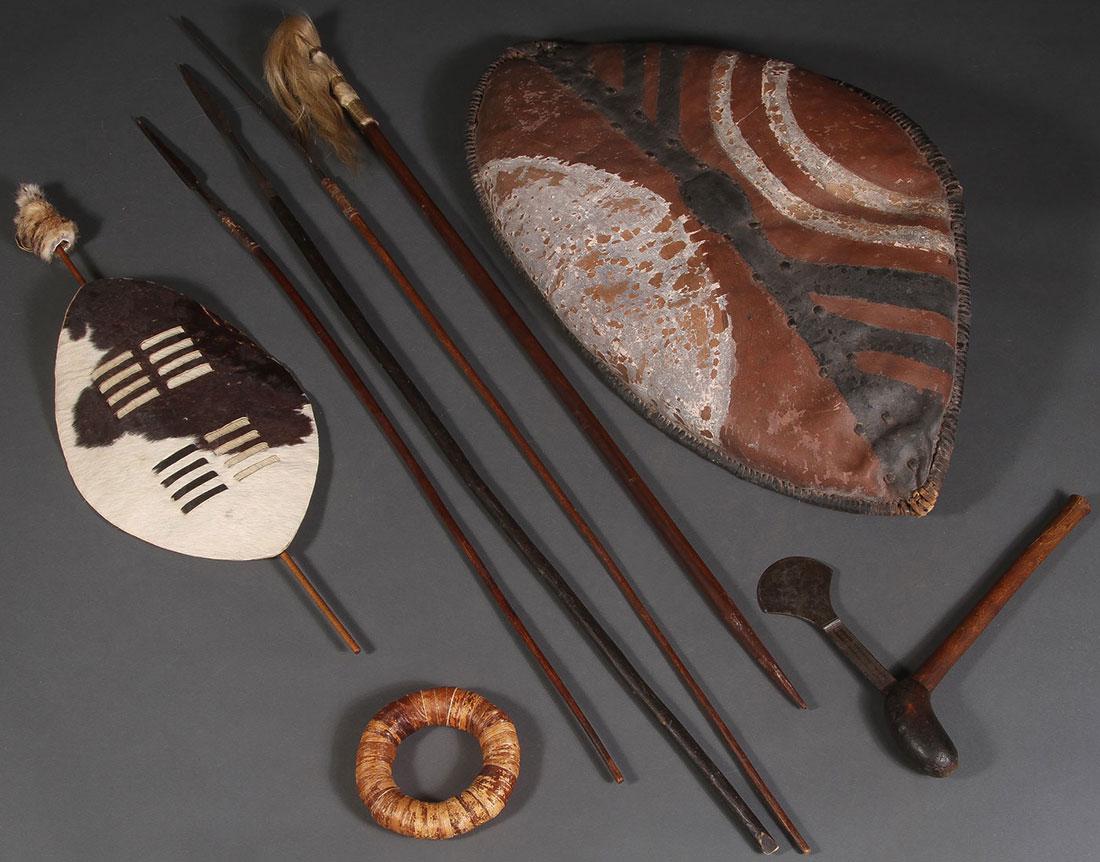 AFRICAN SPEARS AND SHIELDS: AFRICAN SPEARS AND SHIELDS. Comprising two hide shields, three spears, a staff, an ax, and a reed wrapped donut game piece. Greatest length (spear) 65 inches (165 cm). SHIPPING NOTICE: Ja