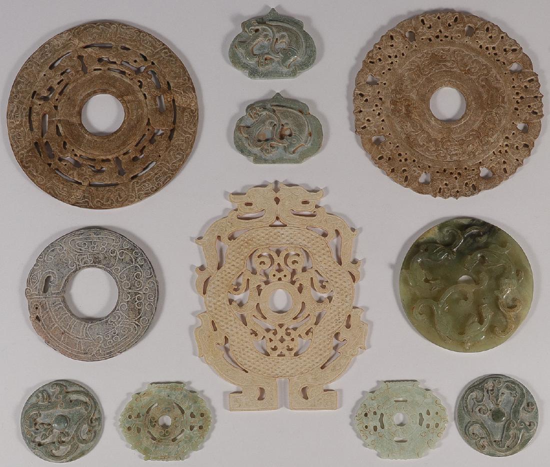 NINE CHINESE CARVED HARDSTONE DISCS: NINE CHINESE CARVED HARDSTONE DISCS. Comprising mostly Archaic style discs, three with pierced carved surfaces and with phoenix and dragon motifs. Together with two shield-shaped relief carved plaques