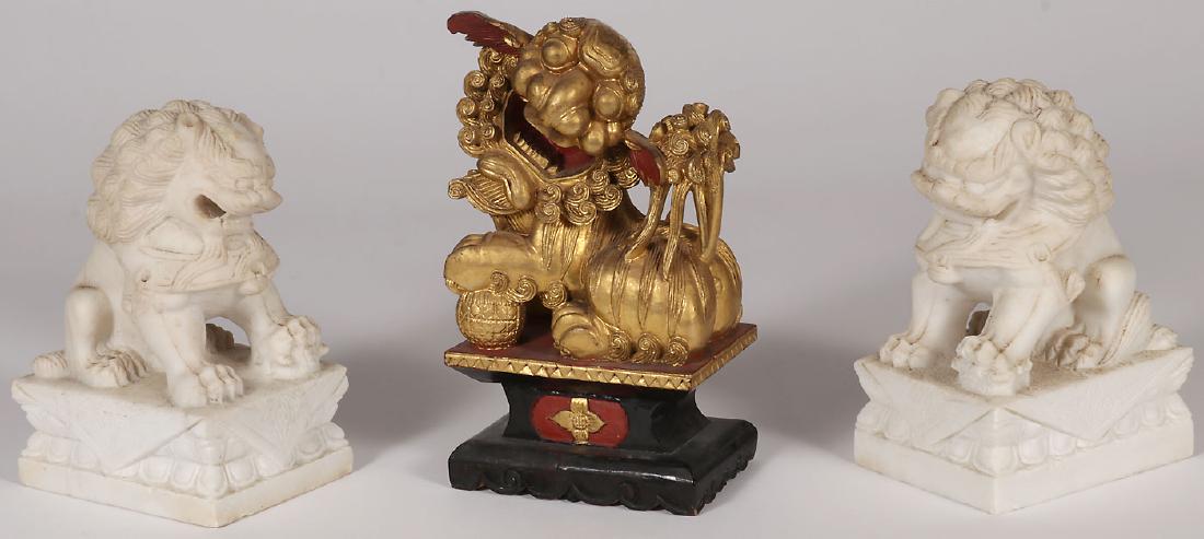 THREE CHINESE CARVED FOO DOGS: THREE CHINESE CARVED FOO DOGS. Comprising a carved and gilt-wood example finely carved in full round with good attention to detail and with red lacquer highlights. Height 10.25 inches (26 cm). Togethe