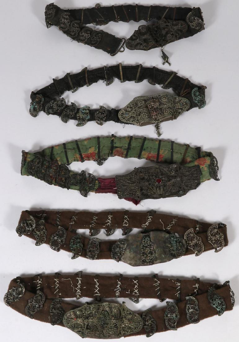 FIVE ETHNIC FILIGREE BELTS, 19TH CENTURY: FIVE ETHNIC FILIGREE BELTS, 19TH CENTURY. Each with ornate filigree buckles and links, some set with faux gemstones and mounted on various types of cloth. Greatest length 36 inches (91.5 cm).