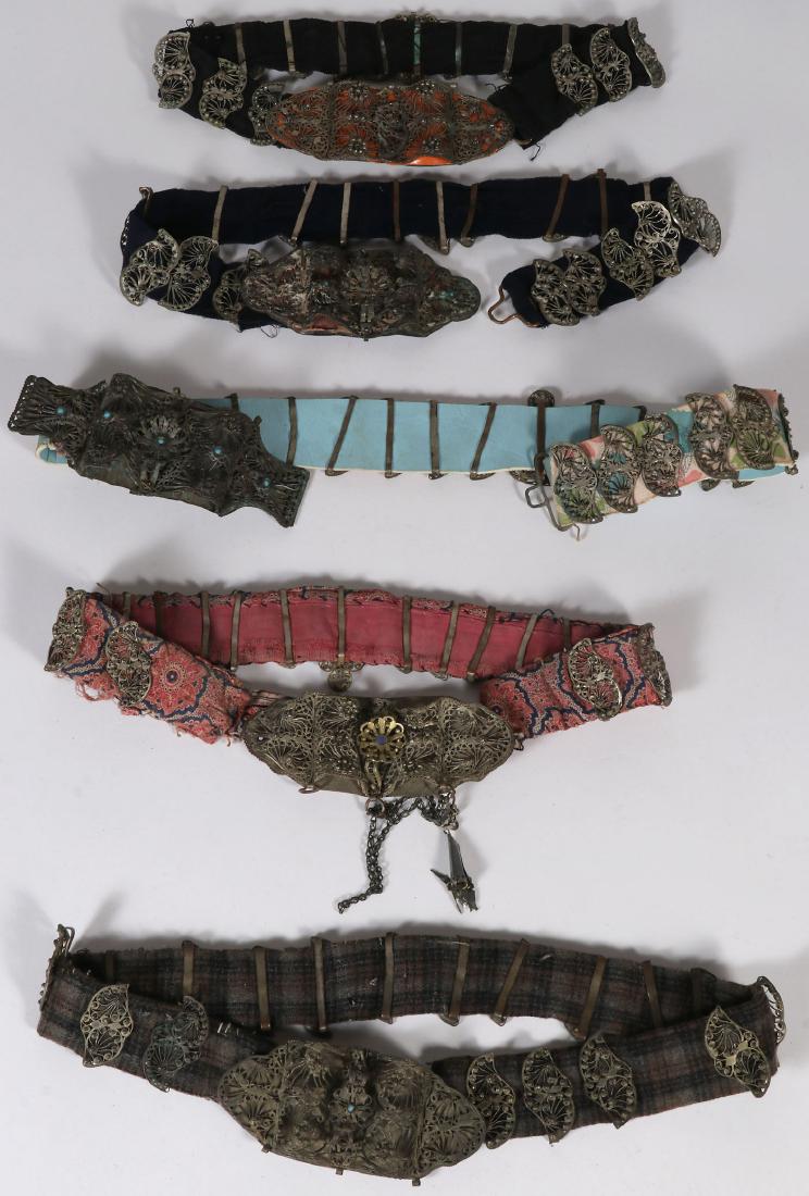 FIVE ETHNIC FILIGREE BELTS, 19TH CENTURY: FIVE ETHNIC FILIGREE BELTS, 19TH CENTURY. Each with ornate filigree buckles and links, some set with faux gemstones and mounted on various types of cloth. Greatest length 35 inches (89 cm).