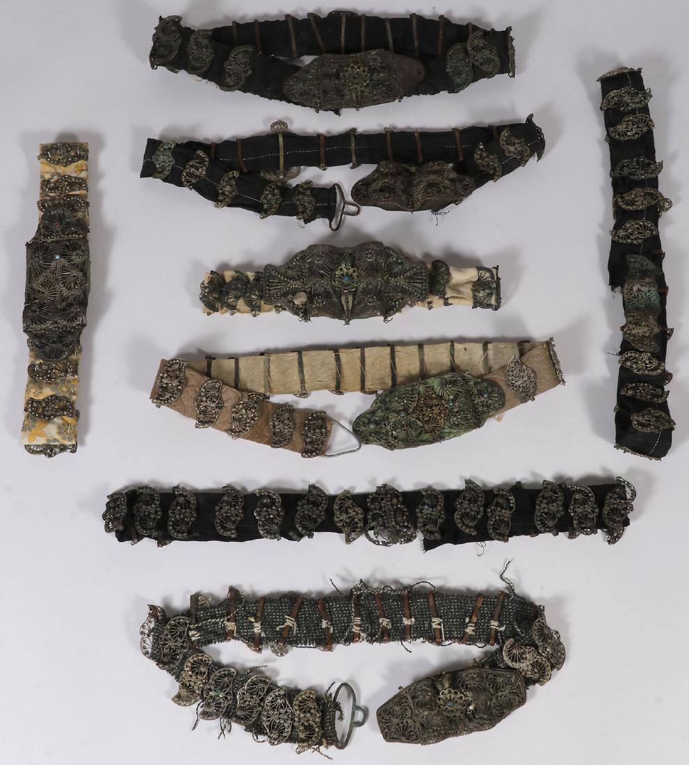EIGHT ETHNIC FILIGREE BELTS, 19TH CENTURY: EIGHT ETHNIC FILIGREE BELTS, 19TH CENTURY. Each with ornate filigree buckles and links, some set with faux gemstones and mounted on various types of cloth. Greatest length 41 inches (104 cm).