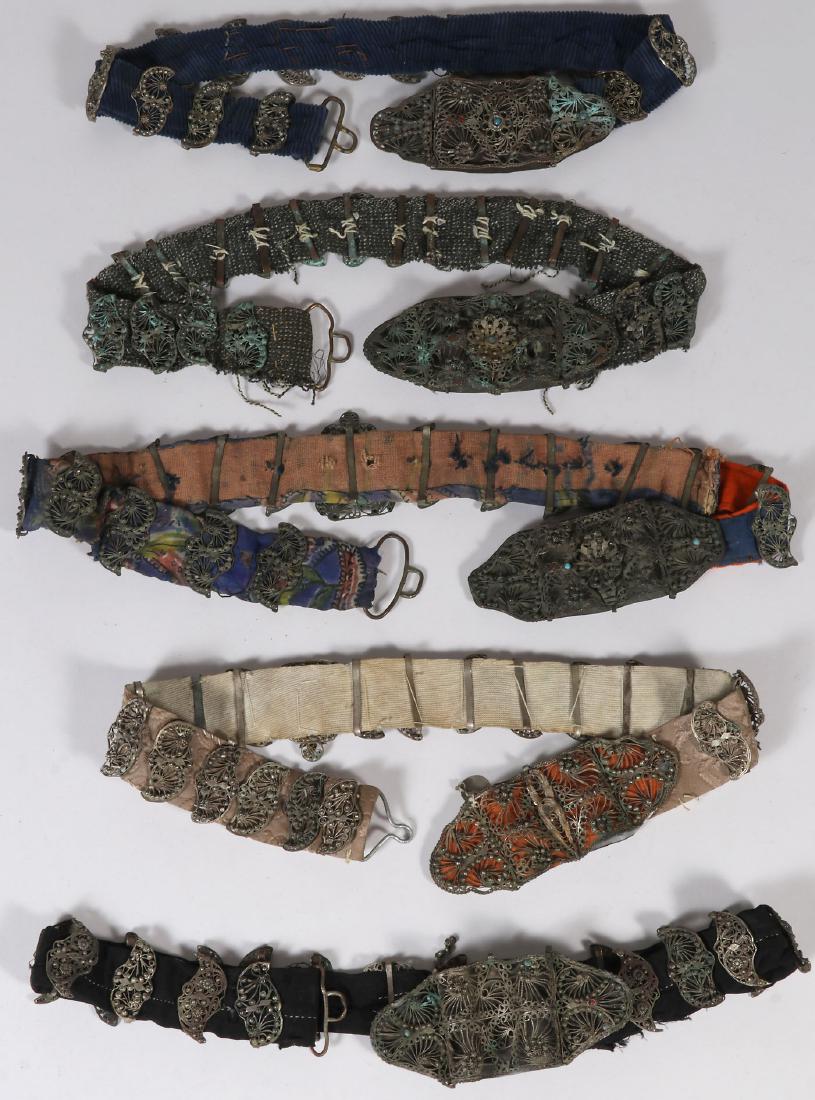 FIVE ETHNIC FILIGREE BELTS, 19TH CENTURY: FIVE ETHNIC FILIGREE BELTS, 19TH CENTURY. Each with ornate filigree buckles and links, some set with faux gemstones and mounted on various types of cloth. Greatest length 37 inches (94 cm).
