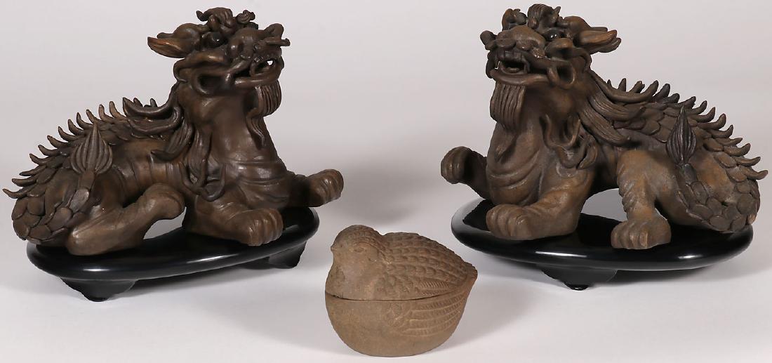 A PAIR OF CHINESE CERAMIC FOO DOGS: A PAIR OF CHINESE CERAMIC FOO DOGS. Both with impressed marks on underside and with black stands and a ceramic covered quail dish. Greatest measurement 11.25 inches (29 cm).