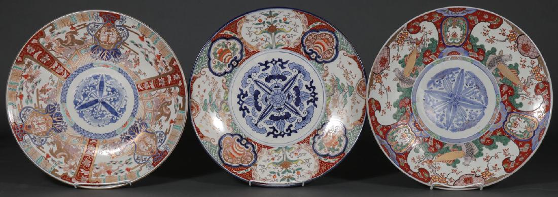 THREE LARGE JAPANESE IMARI CHARGERS, MEIJI: THREE LARGE JAPANESE IMARI CHARGERS, MEIJI. Each profusely decorated in multi-colors and gilt highlights, one with blue underglaze mark on base. Largest diameter 18.6 inches (47.5 cm). SHIPPING NO