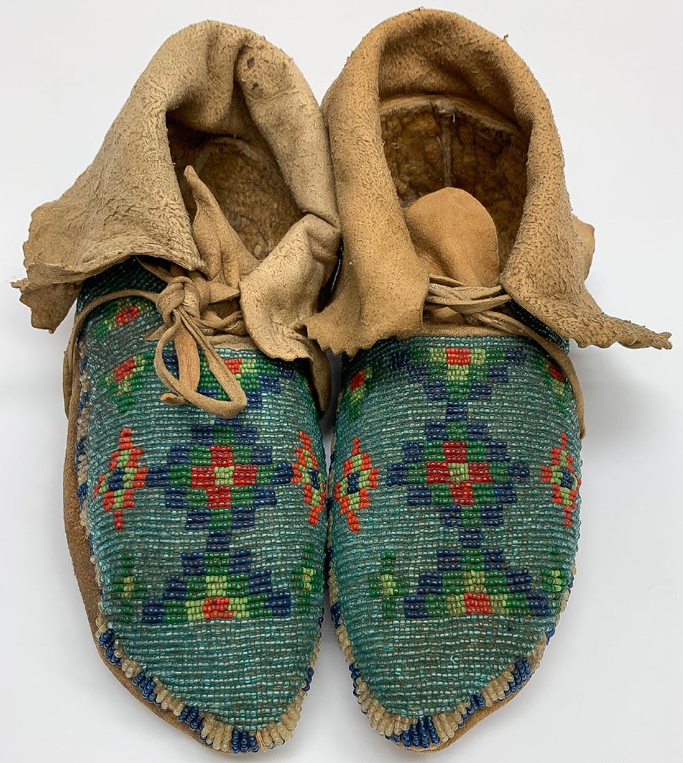 PLATEAU BEADED HIDE MOCCASINS, C. 1910: PLATEAU BEADED HIDE MOCCASINS, C. 1910. Native-tanned with soft soles, the vamps and ankles fully beaded with geometric forms and with supple ankle flaps with saw tooth edging. Very good conditio