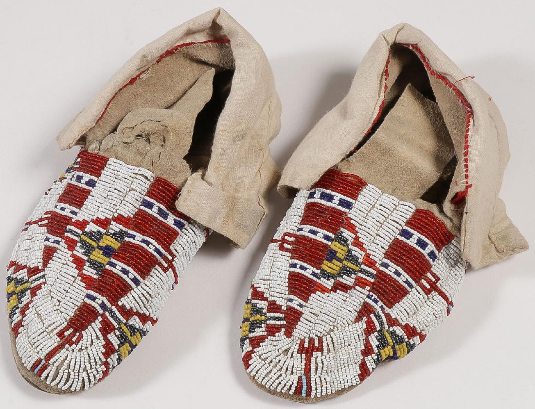 A PAIR OF PLAINS BEADED MOCCASINS, CIRCA 1910: A PAIR OF PLAINS BEADED MOCCASINS, CIRCA 1910. Sinew-sewn, hard soles with thread-sewn ankle flaps. Length 9 inches. SHIPPING NOTICE: Jackson's is your sole and only source for on