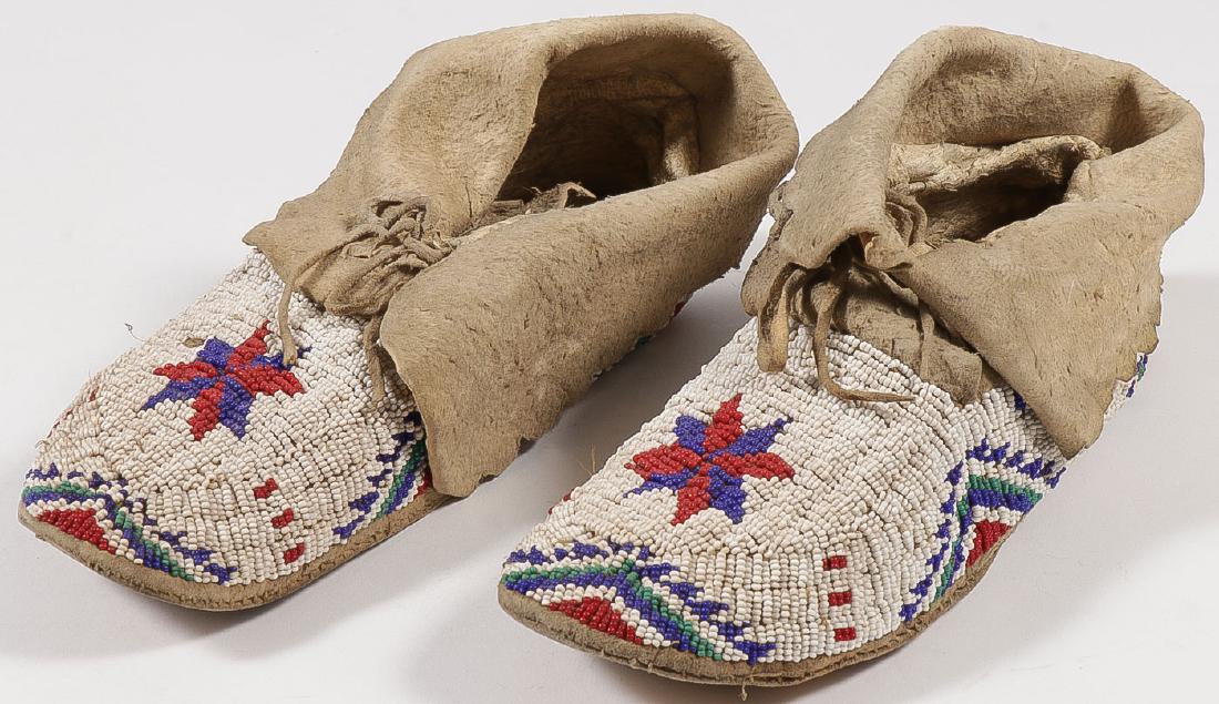A PAIR OF PLAINS BEADED MOCCASINS, CIRCA 1910: A PAIR OF PLAINS BEADED MOCCASINS, CIRCA 1910. Sinew-sewn with hard soles and beaded with geometric designs. Length 10 inches. SHIPPING NOTICE: Jackson's is your sole and only source